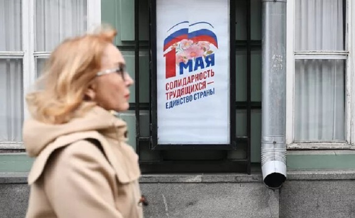 Женщина и плакат к Первому мая. Фото © РИА «Новости»/Илья Питалев